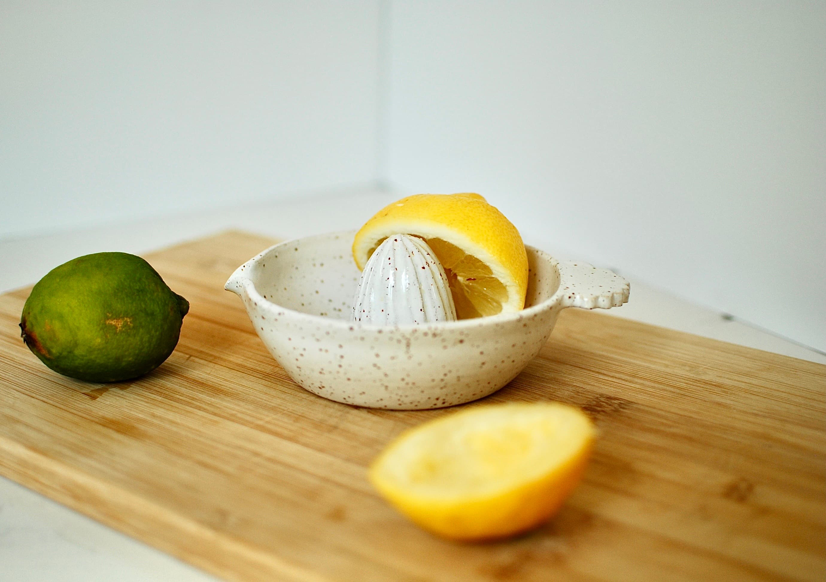 Handmade stoneware citrus juicer with white speckled glaze, styled with lemon and lime on wooden board β Chamonix collection, made in Dublin, Ireland