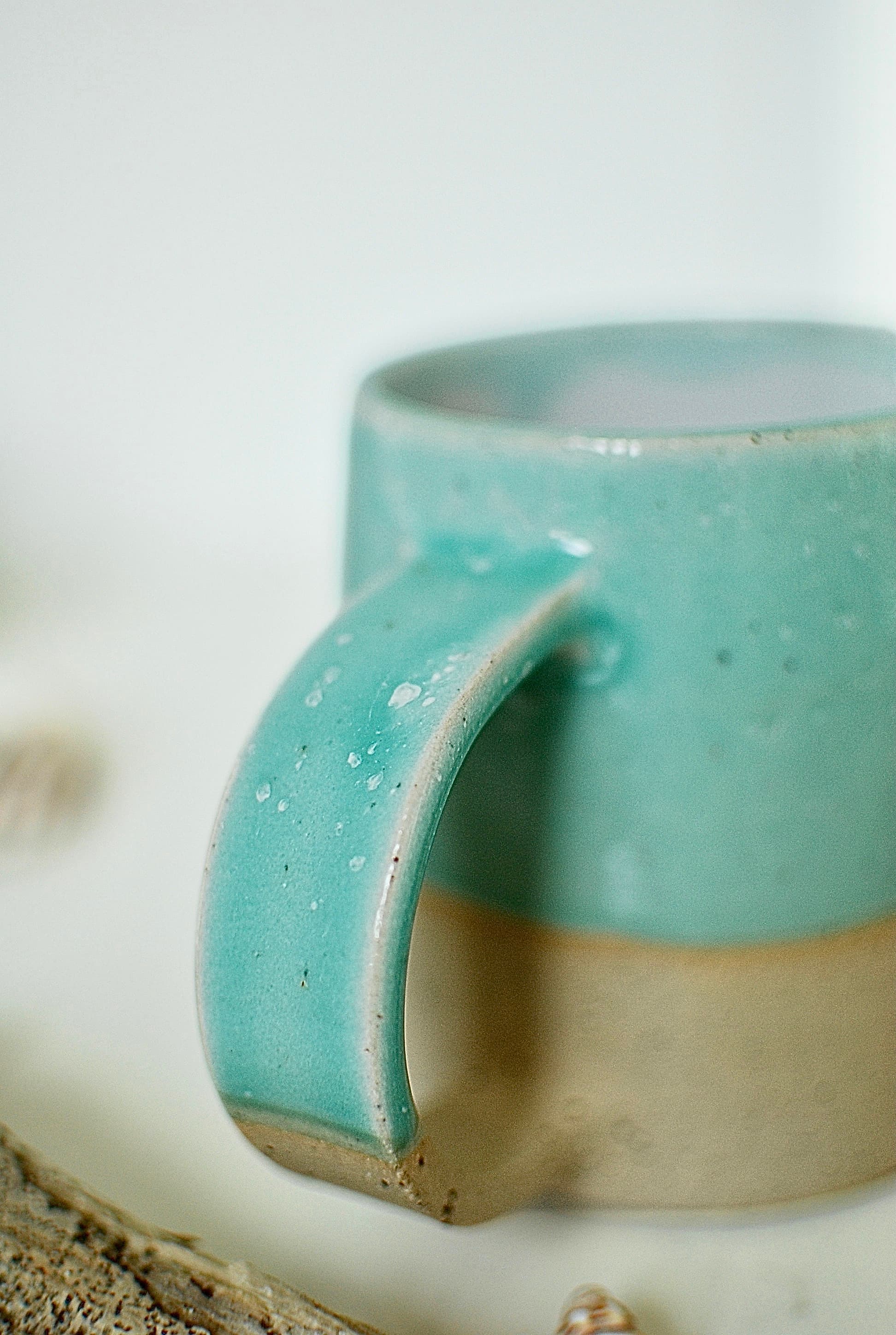Close-up of hand-pulled handle on a wheel-thrown stoneware mug, turquoise glaze with speckled clay detail, Studio Lippi Ceramics Dublin